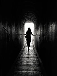 Rear view of silhouette woman standing in tunnel