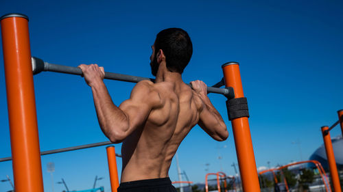 Low angle view of young man exercising against sky