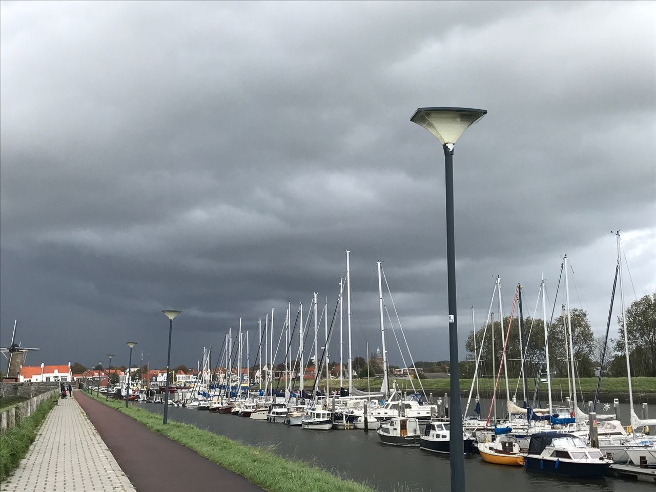 BOATS MOORED IN HARBOR AGAINST SKY