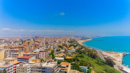 High angle view of buildings and sea against blue sky