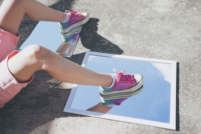 Legs of woman on glass mirror with reflection of sky