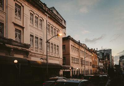 Cars on street by buildings in city against sky