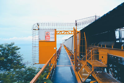 Information sign by bridge against sky