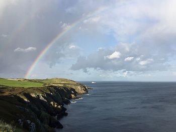 Scenic view of rainbow over sea against sky