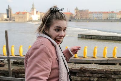 Portrait of smiling woman standing by railing in city