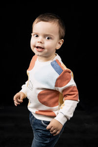 Portrait of cute boy against black background