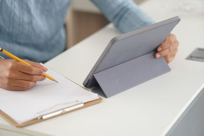 Midsection of man holding paper in pen on table