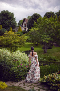 Outdoor portrait of a beautiful luxury brunette woman in a dress with flowers stands