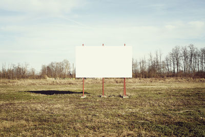 Information sign on field against sky