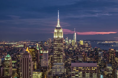 Illuminated empire state building in city against sky at dusk