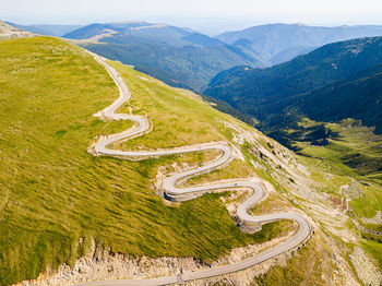 Winding road from high mountain pass, in summer time. aerial view by drone. romania