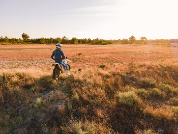 Rear view of woman walking on grassy field