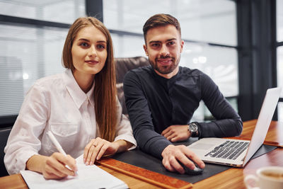 Portrait of smiling woman using laptop at office