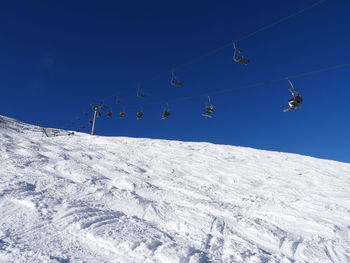 Low angle view of ski lift against clear blue sky