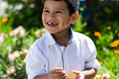 Smiling boy holding flower in park