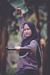 Portrait of smiling young woman standing against trees