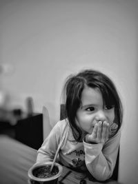 Close-up of cute smiling girl with breakfast sitting on table at home