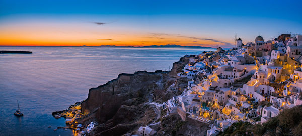 Panoramic view of sea and buildings against sky during sunset