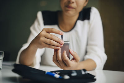 Midsection of woman using mobile phone while sitting on table