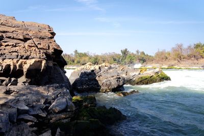 Rock formations by sea against sky