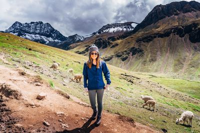 Full length portrait of woman standing on mountain during winter