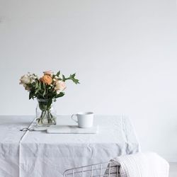 Flowers in vase on table against wall