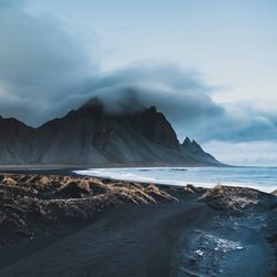 Scenic view of sea by mountains against sky