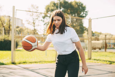 Young cute teen girl leads the ball in a basketball game. a girl plays basketball after school.