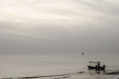 Silhouette man in boat against sky