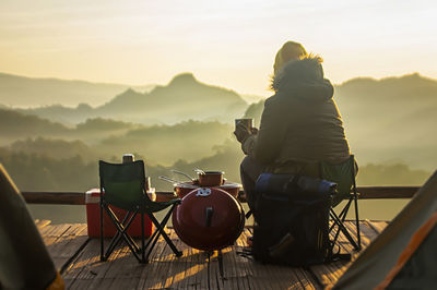 Rear view of man sitting on table at sunset