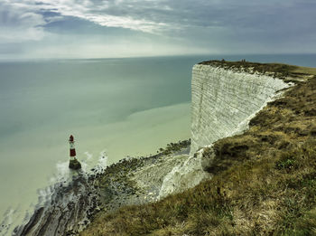 High angle view of lighthouse next to sea against cloudy sky