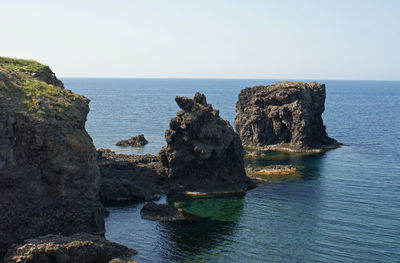 Scenic view of rocks in sea against clear sky
