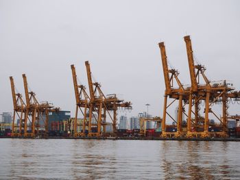 Cranes at commercial dock against clear sky