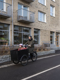 Young mother cycling with two children in cargo bicycle