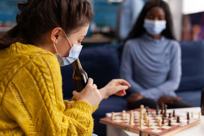 Women wearing mask playing chess at home