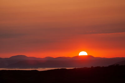 Scenic view of silhouette mountains against romantic sky at sunset