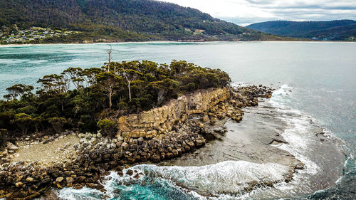 Scenic view of rocks on sea shore against sky