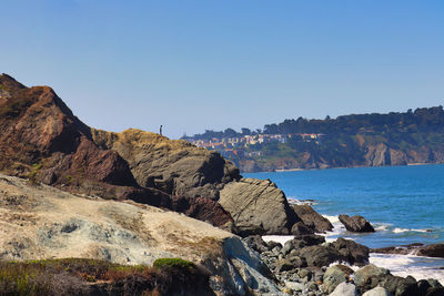 Rock formations on shore against clear sky
