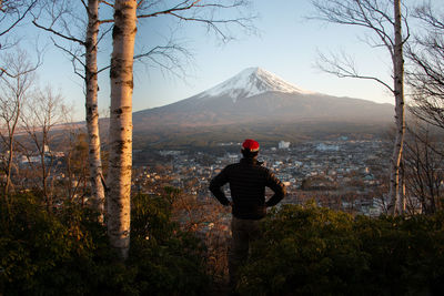 Rear view of man standing on mountain against sky