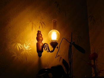 Close-up of illuminated light bulb against wall at night