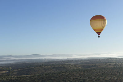 Hot air balloon flying over landscape against clear sky