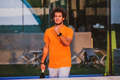 Portrait of young woman standing against wall