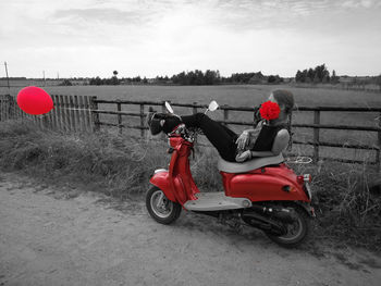 Motorcycle on road by field against sky