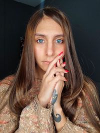 Portrait of young woman against black background