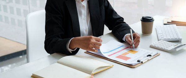 Midsection of businessman working on table