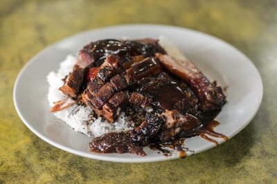 Close-up of roast pork with rice in plate on table