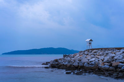 Lighthouse by sea against sky