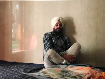 Mature man praying while sitting against wall at gurudwara