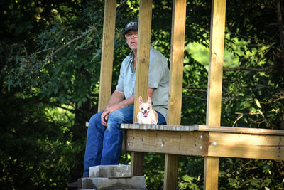 Portrait of senior man sitting with dog on porch