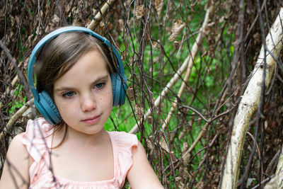 Girl around with a branch and wearing headphones